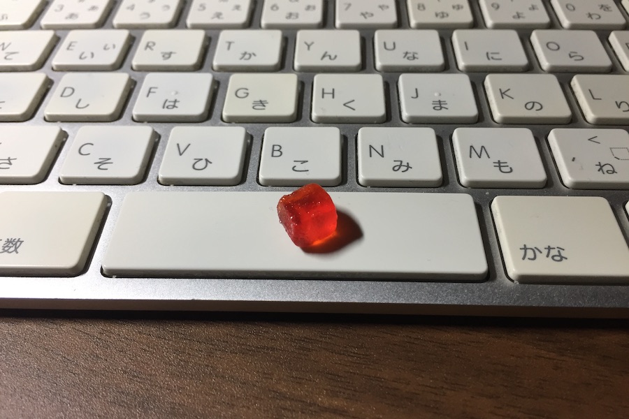 キーボードに乗せられた、1/4にカットされた赤いCBDグミ